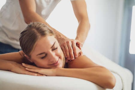 Woman lying face down on a bed, receiving therapeutic massage therapy