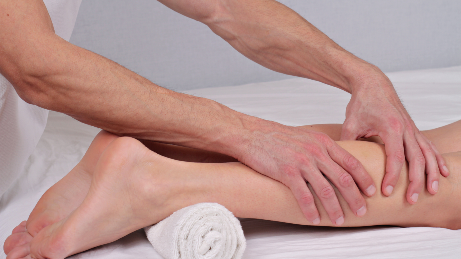 Woman receiving Sports Massage therapy with therapist's hands focusing on her leg.